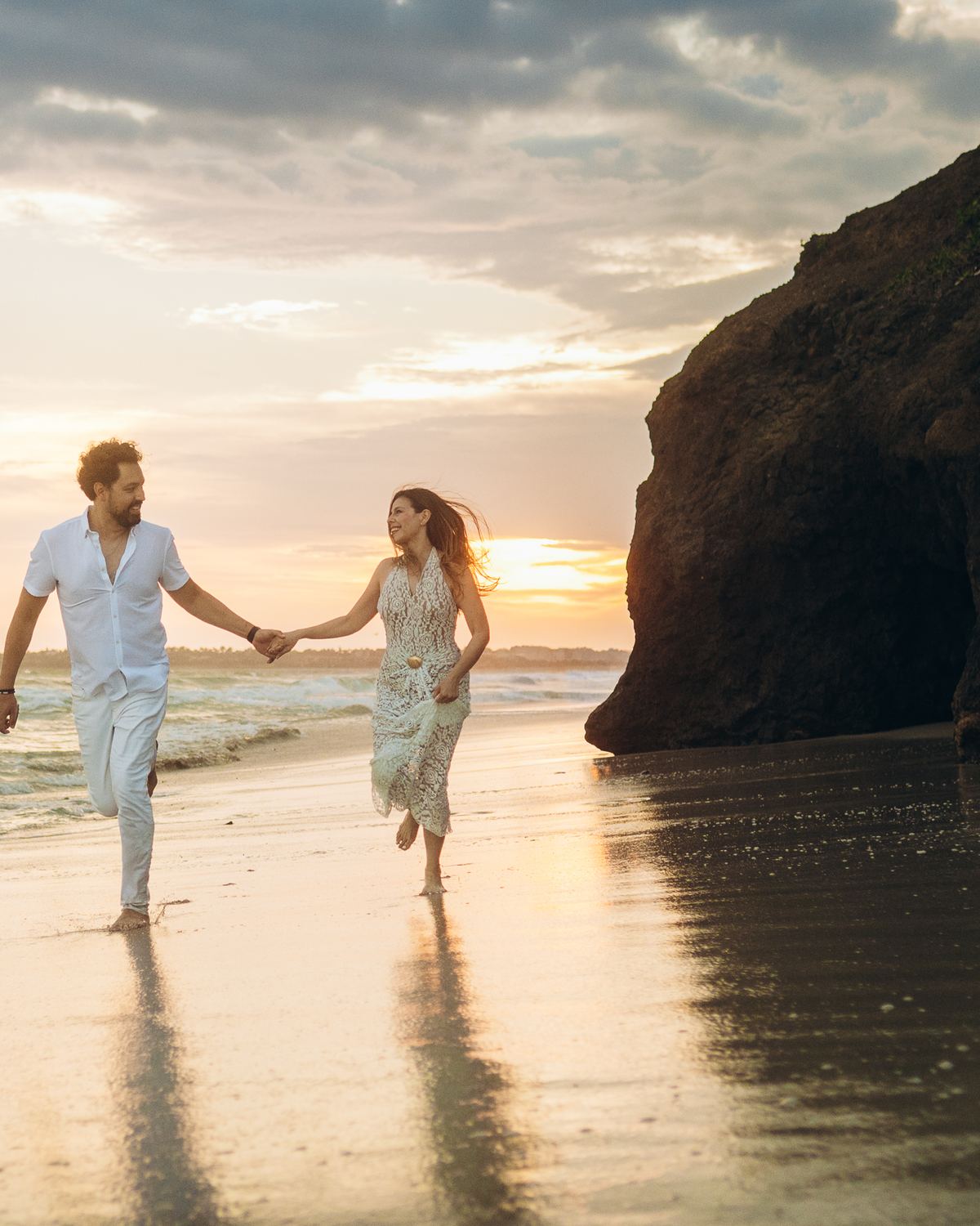 Couple running along the beach at sunset